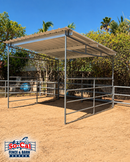 A SoCal Fence and Barn metal horse shelter with a corrugated roof, set outdoors on a sandy ground with trees and blue sky in the background.